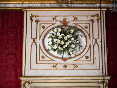 Grossi specchi dalle cornici in oro si alternano a riquadri con ghirlande di fiori bianchi aggettanti